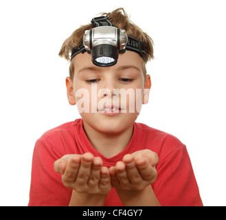 Portrait of boy avec torche sur sa tête sur fond blanc. Souriant, il regarde ses mains. Banque D'Images