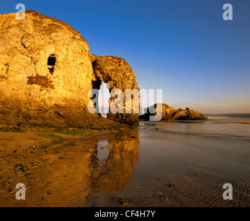 Arch Rock à Droskyn Point, Broad Oak, reflétée dans le sable humide avec chapelle Rock en arrière-plan. Banque D'Images