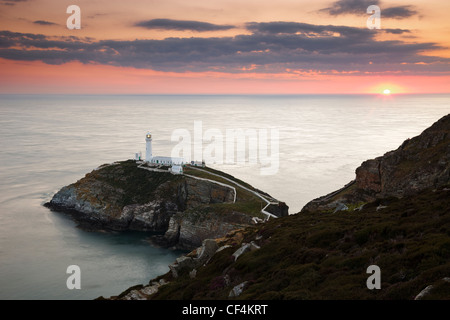 Le coucher de soleil sur l'horizon derrière phare de South Stack, un phare spectaculaire juste à côté de l'Île saint sur la compagnie du nord-ouest Banque D'Images