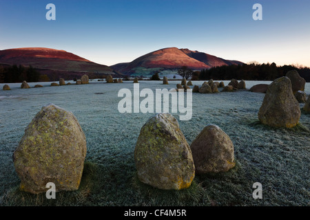 Sur un cercle de pierres de Castlerigg frosty matin tandis que les premiers rayons de lumière sur les pentes de Blencathra dans le Lake District. Banque D'Images