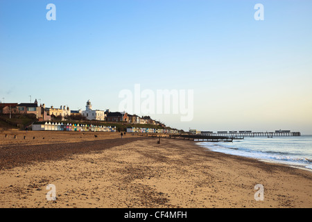 Une vue le long de la plage de sable à Southwold et les cabanes de plage, le phare et la jetée. Banque D'Images