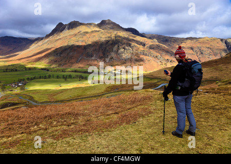 Une femme à l'aide d'un appareil GPS de poche en marchant dans les collines au-dessus de la vallée de Langdale. Banque D'Images