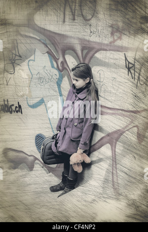 Girl standing dans un escalier avec graffiti avec une valise et un ours en peluche Banque D'Images