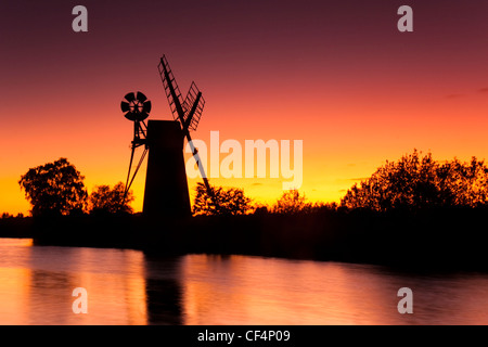 Turf drainage Fen moulin sur les Norfolk Broads silhouetté contre un ciel du soir rouge. Banque D'Images