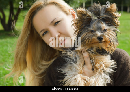 Jeune fille en journée ensoleillée holding yorkshire terrier chien de se concentrer sur. Banque D'Images