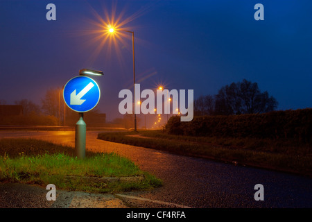 Un panneau routier indiquant de rester à gauche, allumé jusqu'au crépuscule. Banque D'Images