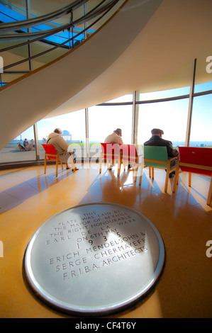 Une plaque commémorant l'ouverture de la De La Warr Pavilion en 1935 et les gens à l'intérieur de détente en profitant de la vue sur la mer. T Banque D'Images