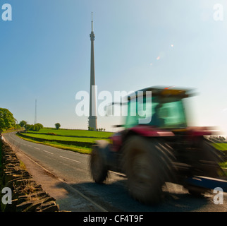 Un tracteur voyageant le long d'une route sur le passé Emley Moor Emley Moor Tower, une tour de transmission de télévision qui est le plus haut Banque D'Images