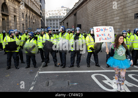 Une jeune femme manifestant vêtu d'un tutu et brandissant une pancarte en face d'une ligne de policiers anti-émeute lors du G20 de protestation. Poli Banque D'Images