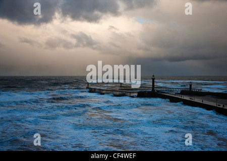 Matériel roulant dans les vagues d'une mer rugueuse autour de l'Est et l'ouest des jetées à Whitby. Banque D'Images