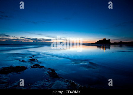 Château de Bamburgh, ancienne résidence des rois de Northumbrie, situé sur un grand whinstone rocheux, se découpant dans le pré-aube ligh Banque D'Images