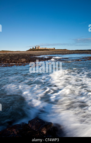 Le reste du château de Dunstanburgh construit sur un promontoire dominant un spectaculaire de la côte de Northumberland. Banque D'Images