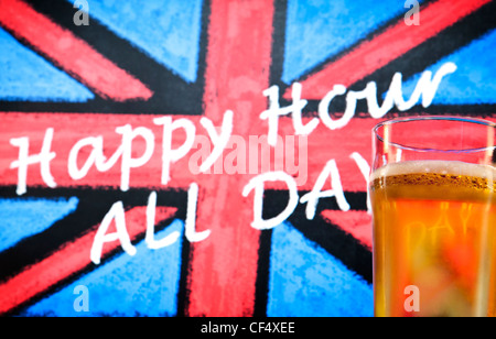 Tableau noir enseigne de pub avec une craie appelée Union Jack, qui se lit 'happy hour' toute la journée et une pinte de bière en verre à l'avant-plan Banque D'Images