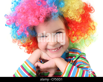 Petite fille en perruque clown smiling and looking at camera, le menton sur les mains, moitié du corps, isolé Banque D'Images