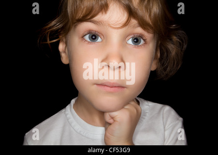 Une petite fille en blanc T-shirts isolé sur fond noir Banque D'Images