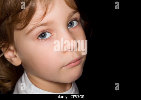 Petite fille en blanc T-shirts isolé sur fond noir Banque D'Images