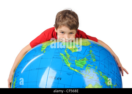 Garçon en chemise rouge se trouve sur inflatable globe isolé sur fond blanc Banque D'Images