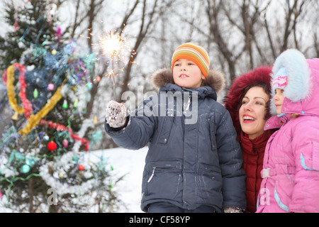 Mère et ses deux enfants est debout près de l'arbre de Noël et à la lumière dans le Bengale occidental à la main du garçon. Banque D'Images