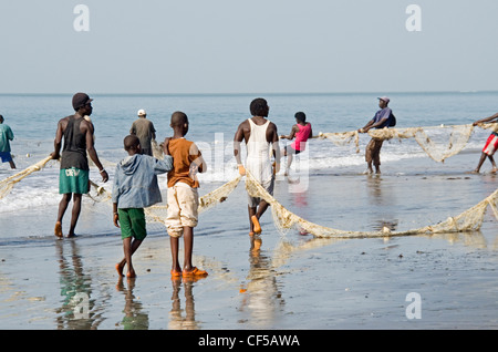 Les pêcheurs locaux courriers dans les filets de l'océan Atlantique sur la plage de Kololi Gambie Afrique de l'ouest Banque D'Images