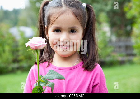 Allemagne, Bavière, Huglfing, Girl holding flower in jardin, smiling, portrait Banque D'Images