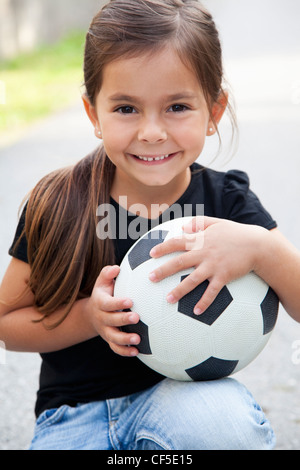 Allemagne, Bavière, Huglfing, Girl with ball on street, smiling, portrait Banque D'Images