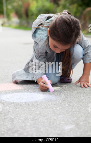 Allemagne, Bavière, Huglfing, Girl drawing on street with chalk Banque D'Images