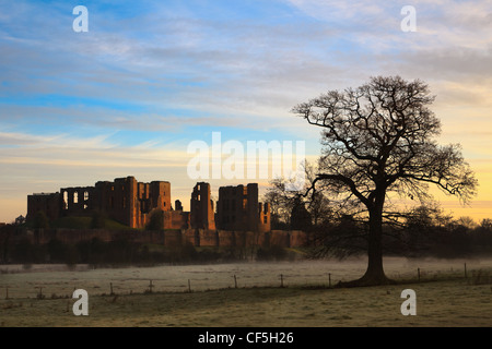 Les ruines de château de Kenilworth Warwickshire dans avec un arbre isolé contre un hiver aube skyline Banque D'Images