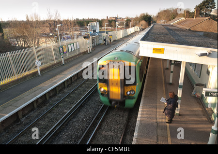 Train arrivant en gare de l'Est Ewell avec une lecture de banlieue sur la plate-forme à 8h30 Banque D'Images