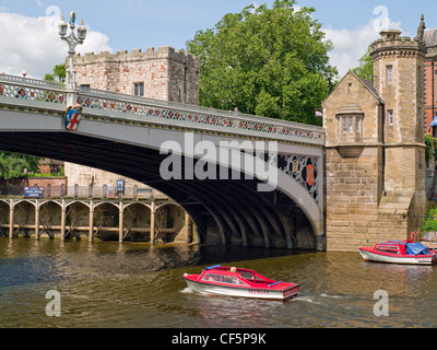 Un petit navire de plaisance en passant sous le pont Lendal sur la rivière Ouse par Lendal Tower. Banque D'Images