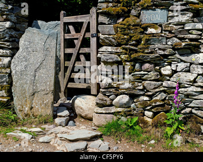 Panneau indiquant la direction à Rydal à côté d'une porte dans un mur de pierres sèches. Banque D'Images