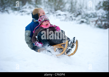 Mère et fille dans la neige sur un traîneau en bois traditionnel. Banque D'Images