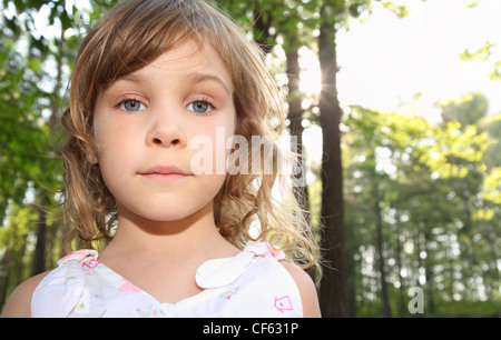 Portrait de petite fille mignonne avec des cheveux blonds en blanc à l'intérieur de la forêt verte Banque D'Images