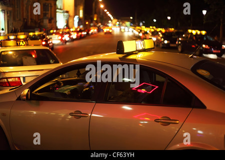 La vie nocturne de la ville. quelques taxis serrage sur route. De nombreuses lumières lumineuses Banque D'Images