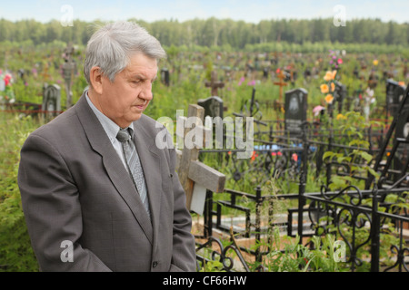 Ancien senior triste costume gris dans l'article sur le cimetière et à la tombe, à l'été Banque D'Images