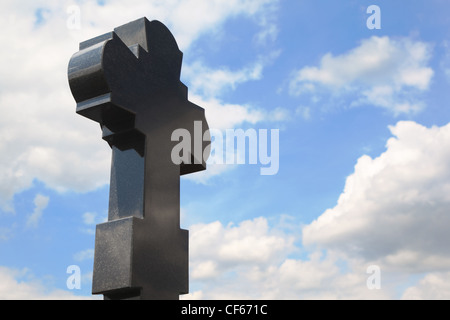 Croix de granit noir sur Cemetery, ciel bleu avec des nuages Banque D'Images