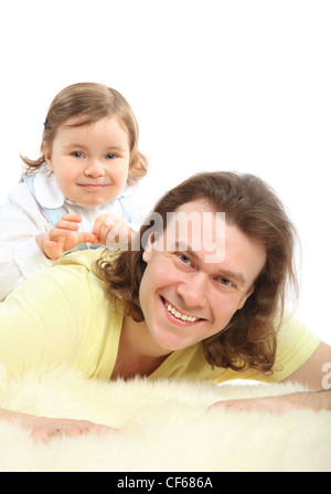 Petite fille heureuse siège au père qui allongé sur le tapis de fourrure blanche Banque D'Images