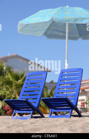 Deux chaises vides en plastique, sur le côté, stand du sable dans le cadre de jour ouvert parasol Banque D'Images