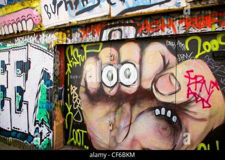 Le Graffiti d'un poing et divers autres éléments de portes et murs dans Brick Lane. Banque D'Images