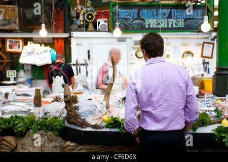 Un client d'un étal de poisson frais à Borough Market. Banque D'Images