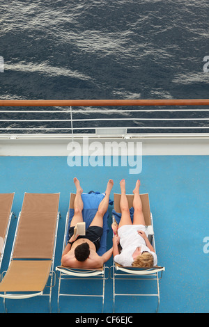 Couple : l'homme et la femme à la fois de vous détendre sur des chaises longues. Banque D'Images