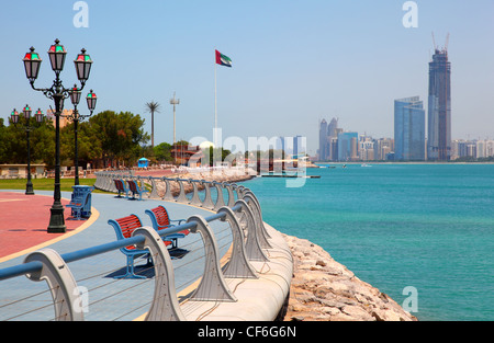 Bancs de parc en rouge sur le front de mer dans le contexte de bâtiments d'Abu Dhabi Banque D'Images