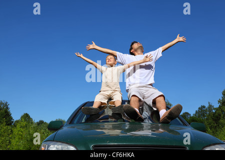 Avec Père fils s'asseoir sur toit de voiture, Ascenseur, personne dans le ciel et largement mettre les mains Banque D'Images