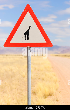 Girafe crossing sign le long d'une route de gravier. La Namibie Banque D'Images