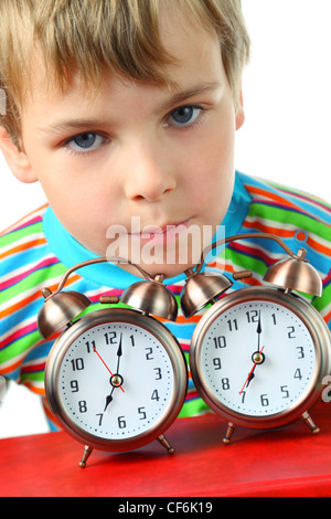 Petite blonde boy in striped shirt posait sa tête sur deux alarmes Banque D'Images