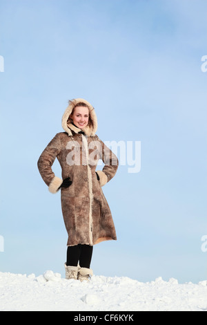 Girl mettant les mains sur la taille se tient sur la neige en hiver Banque D'Images