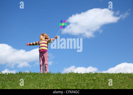 Jeune fille se tient sur l'herbe en été a l'air de côté et tient en main moulin Banque D'Images