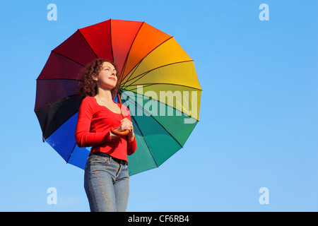 Fille se tient contre le ciel bleu, tenant un parasol sur la couleur et regarde bien Banque D'Images