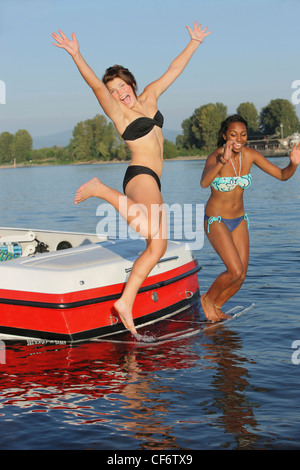 Adolescentes sauter d'un bateau dans l'eau ; Troutdale Oregon United States of America Banque D'Images