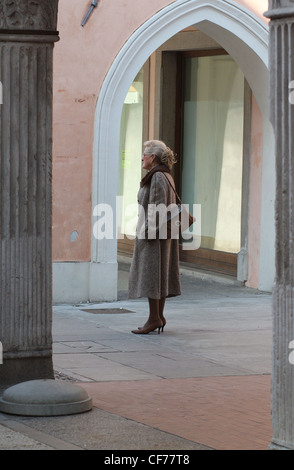 Une femme âgée en attente d'amis dans le centre-ville de San Daniele del Friuli, Italie. Banque D'Images