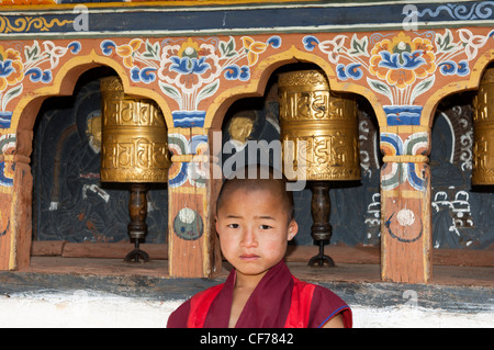 Moine Bouddhiste infantile comité permanent par la prière mills dans le Temple de la fertilité Chimi Lhakhang, Lobesa, Bhoutan Banque D'Images